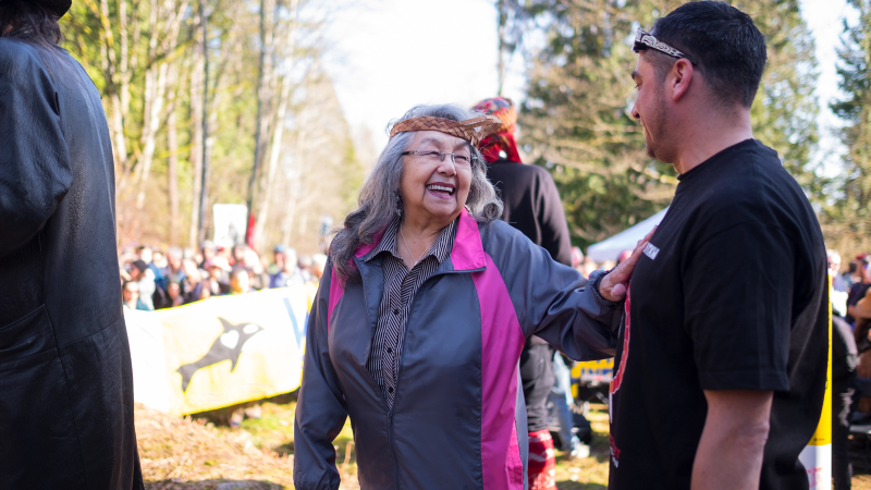 Will George (right) welcomes a visitor to the watch house with protestors from the March 10 march in the background.